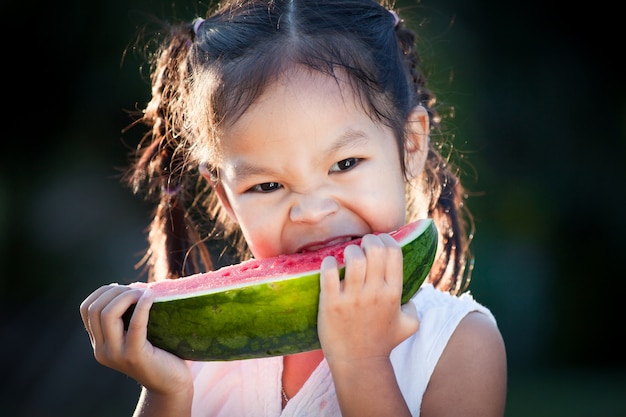 Linda niña asiática niño comiendo sandía fruta fresca