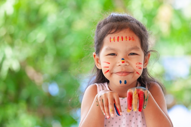 Linda niña asiática del niño con las manos pintadas sonriendo con diversión y felicidad