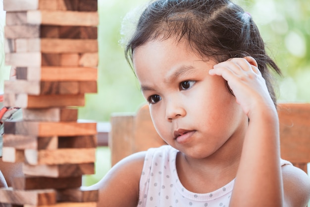 Linda niña asiática niño prestar atención para jugar juegos de pila de bloques de madera