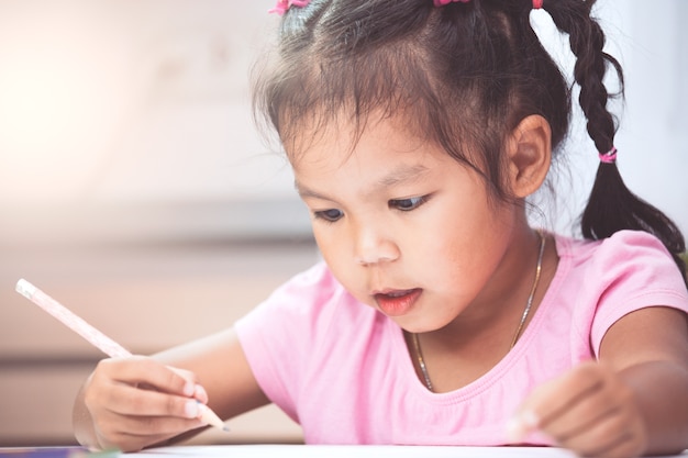 Linda niña asiática niño que se divierte dibujar y pintar con lápiz de color vintage