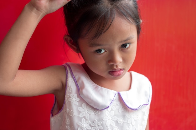 Linda niña asiática del niño sobre fondo rojo.