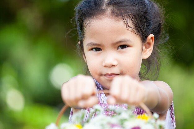 Linda niña asiática niño sosteniendo cesta de hermosas flores en el jardín