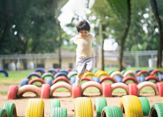 Linda niña asiática sonríe y juega en la escuela o en el patio de la guardería o en el patio de recreo Actividad de verano saludable para niños Niña asiática escalando al aire libre en el patio de recreo Niño jugando en el patio de recreo al aire libre