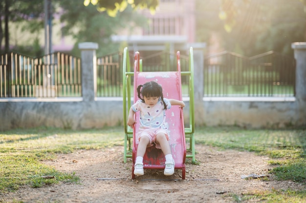 Linda niña asiática sonríe jugar en la escuela o en el patio de la guardería o en el patio de recreo Actividad de verano saludable para niños Niña asiática escalando al aire libre en el patio de recreo Niño jugando en el patio de recreo al aire libre