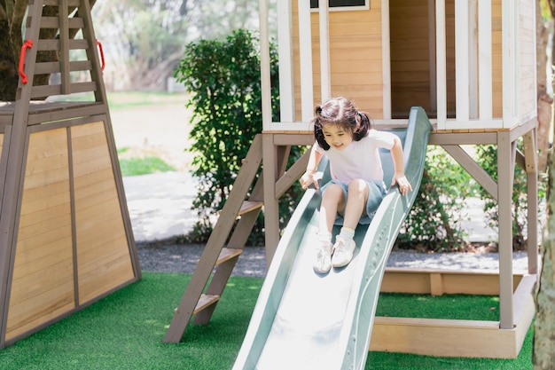 Linda niña asiática sonríe jugar en la escuela o en el patio de la guardería o en el patio de recreo Actividad de verano saludable para niños Niña asiática escalando al aire libre en el patio de recreo Niño jugando en el patio de recreo al aire libre