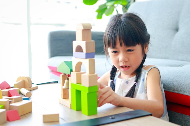 Linda niña asiática Sonriendo feliz jugando con juguetes de madera concepto de aprendizaje y desarrollo de habilidades de niños en edad escolar