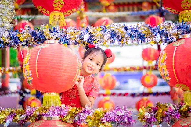 Linda niña asiática en traje tradicional chino sonriendo en el templo. Feliz año nuevo chino concepto.