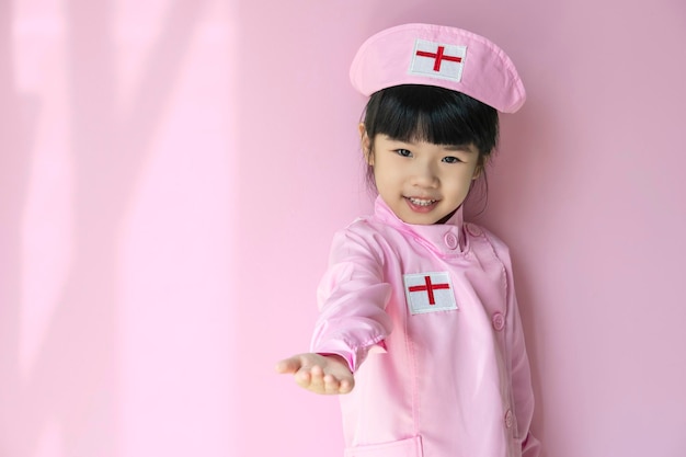 Una linda niña asiática con uniforme médico juega a la enfermera Foto de perfil de un niño pequeño y sonriente diviértete disfruta del juego del hospital Concepto de salud