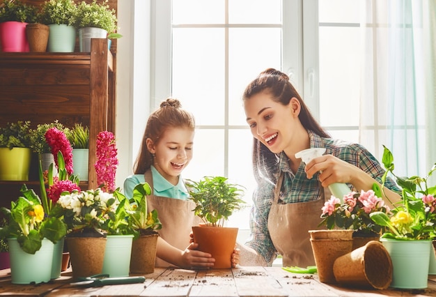 Linda niña ayuda a su madre a cuidar las plantas Mamá y su hija se dedican a la jardinería