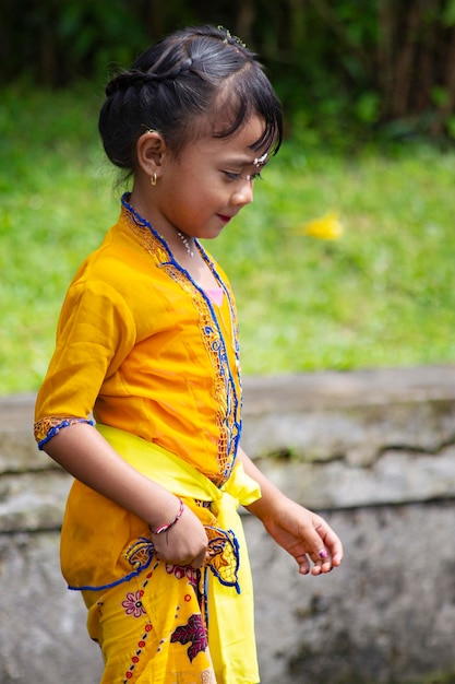 Linda niña balinesa sonriente vistiendo un traje tradicional durante la ceremonia del templo, Bali, Indone