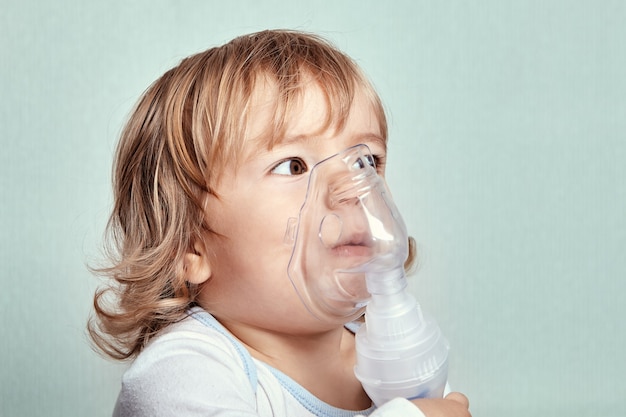 Linda niña blanca de unos 2 años está usando un nebulizador para detener un ataque de asma.