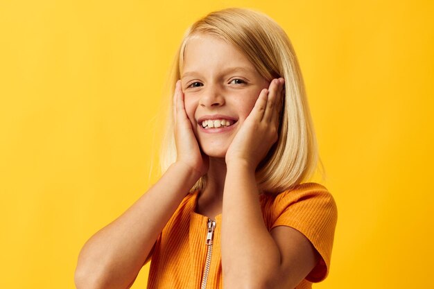 Linda niña con cabello rubio posando fondo amarillo