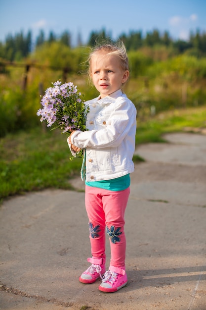 Linda niña caminando con un ramo de flores