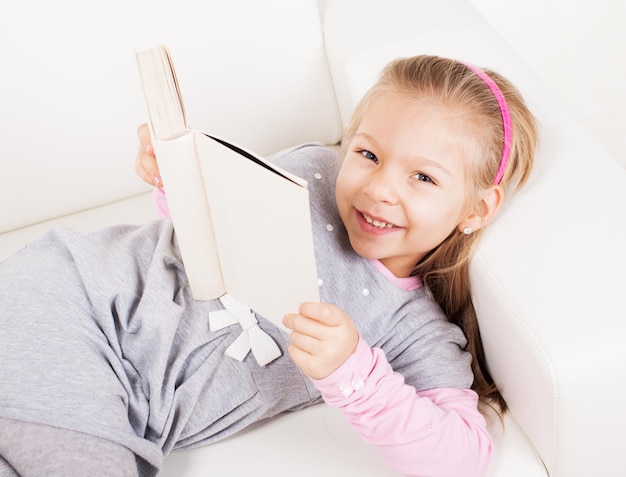 Linda niña en casa leyendo un libro.