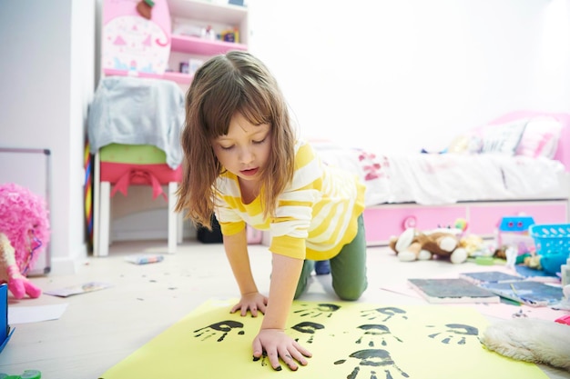 linda niña en casa pintando con las manos graciosa sin sonrisa de dientes