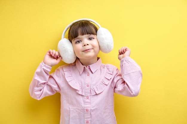 Linda niña caucásica en blusa escucha música en auriculares y baila con grandes auriculares inalámbricos...