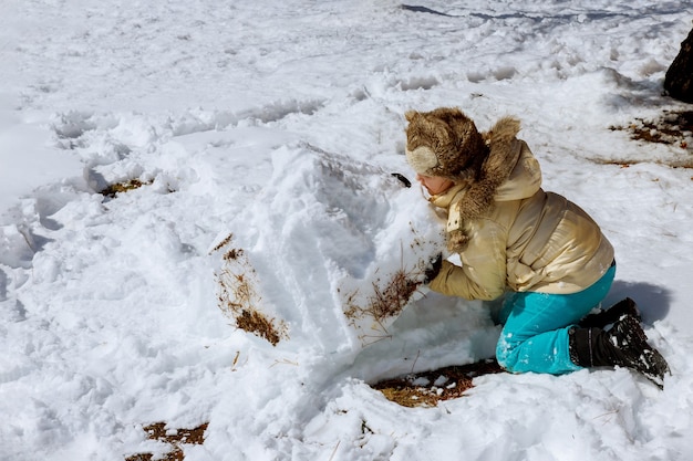 Linda niña caucásica jugando en la nieve del invierno en un niño