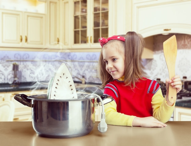 Linda niña cocinando plancha en la olla