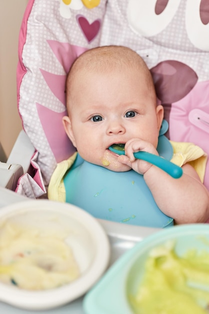 Foto linda niña comiendo con cuchara en la cocina