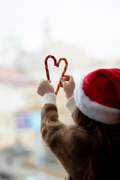 Una linda niña decora las ventanas Ambiente navideño de Año Nuevo