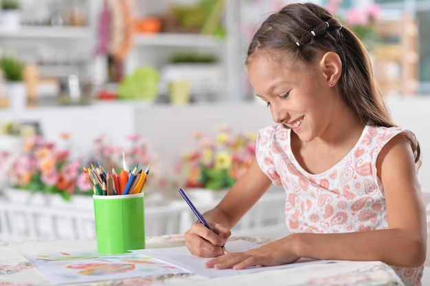 Foto linda niña dibujando con lápices de colores en casa