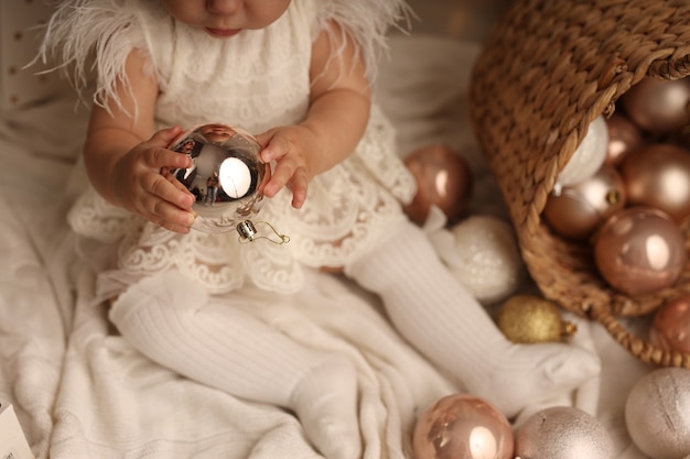 linda niña en un disfraz de Navidad jugando con bolas de árbol de Navidad