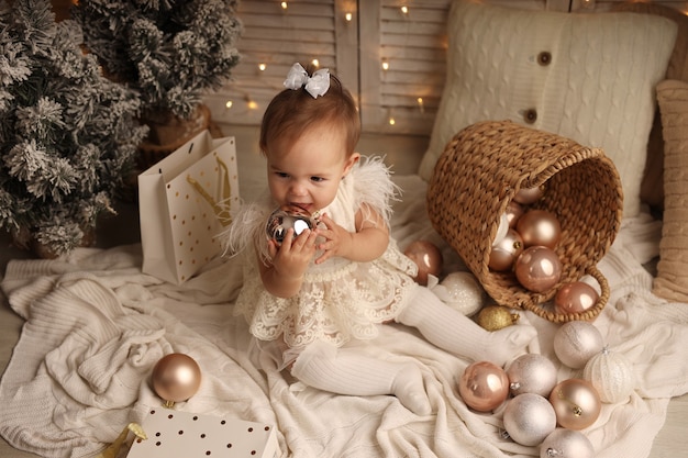 linda niña en un disfraz de Navidad jugando con bolas de árbol de Navidad