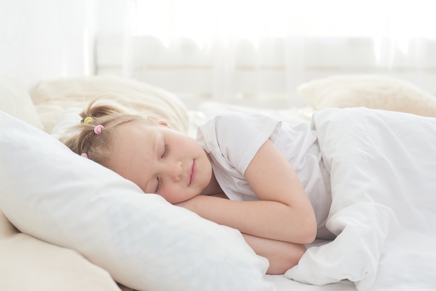 Una linda niña disfruta de una siesta en la cama después de la cena.