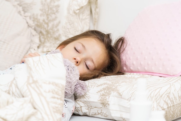 Una linda niña durmiendo en la cama debajo de una manta con un osito de peluche Retrato de un niño dormido Dormir con su juguete suave favorito