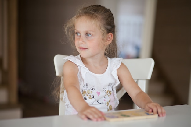 Linda niña en edad preescolar jugando juegos educativos con figuras de plastilina preparándose para la escuela en el jardín de infantes