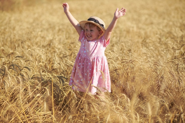 Una linda niña se encuentra en un campo de trigo.