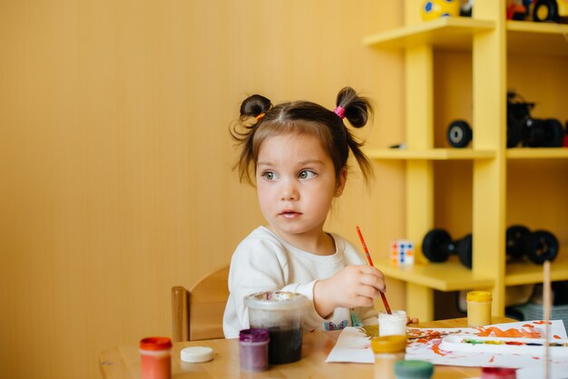 Una linda niña está jugando y pintando en su habitación. Recreación y entretenimiento.