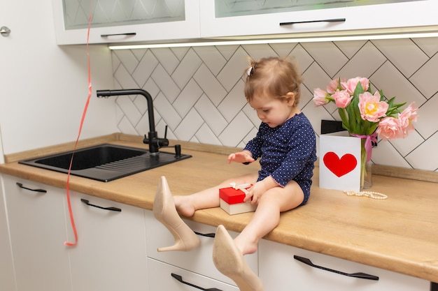 Una linda niña está sentada en la cocina con un ramo de tulipanes rosados hermosa postal de regalo