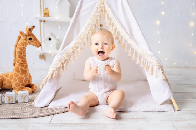 Una linda niña está sentada en una luminosa y acogedora sala de juegos para niños Textiles para niños para la guardería Un niño feliz