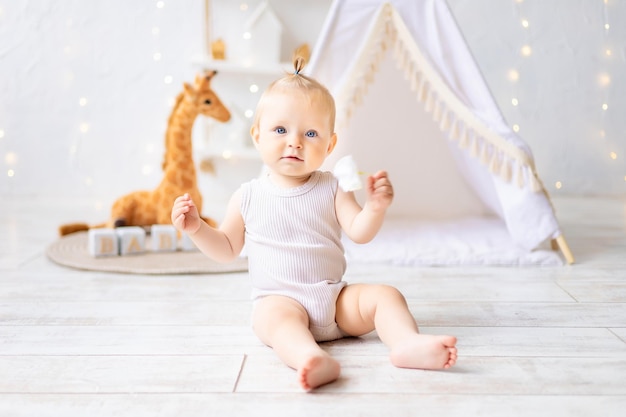 Una linda niña está sentada en una luminosa y acogedora sala de juegos para niños Textiles para niños para la guardería Un niño feliz