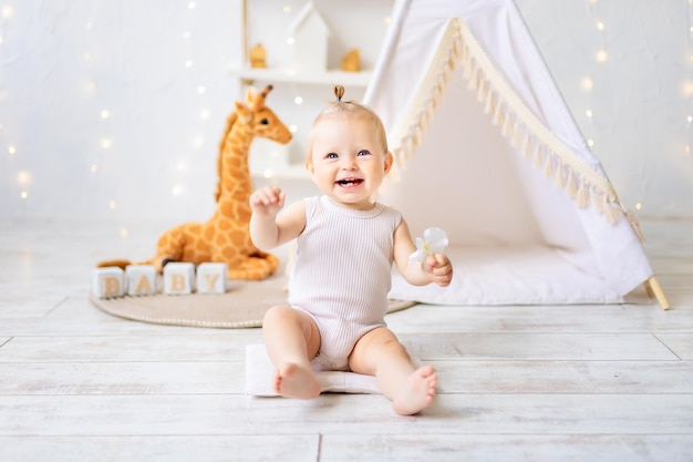 Una linda niña está sentada en una luminosa y acogedora sala de juegos para niños Textiles para niños para la guardería Un niño feliz