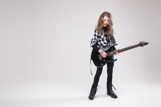 Linda niña estrella de rock niña tocando la guitarra eléctrica y cantando canción rodeada de globos