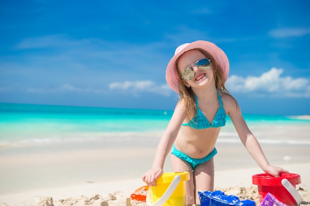 Linda niña feliz jugando con juguetes en vacaciones en la playa