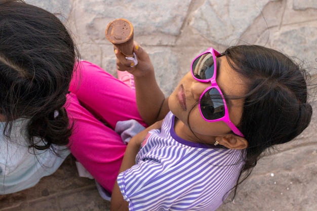 Linda niña con gafas de sol comiendo un delicioso helado