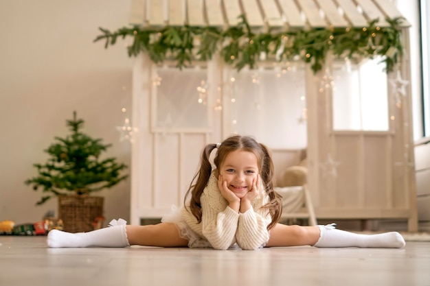 Una linda niña gimnasta está sentada en una división