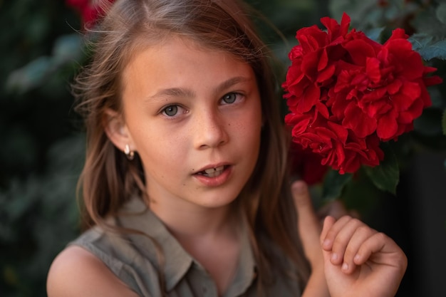 Linda niña hermosa con dientes torcidos cerca de una rosa