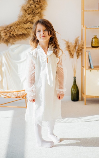 Una linda niña con un hermoso vestido está bailando en una habitación luminosa y soleada. La luz del sol cae desde la ventana.