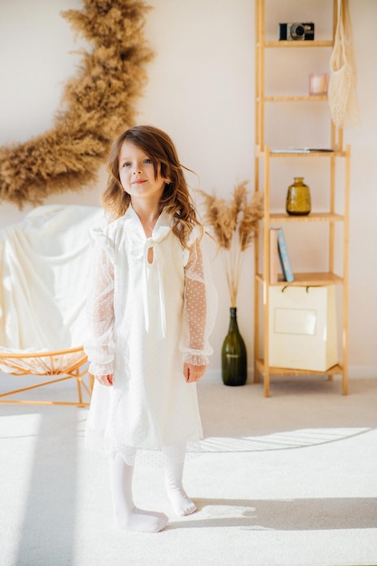 Una linda niña con un hermoso vestido está bailando en una habitación luminosa y soleada. La luz del sol cae desde la ventana.