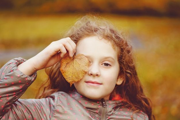 Linda niña con hojas de otoño