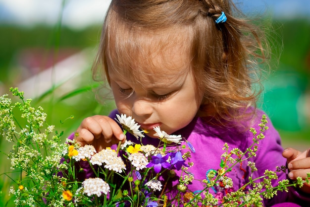 Foto linda niña huele flores, horario de verano