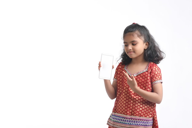 Linda niña india mostrando smartphone sobre fondo blanco.