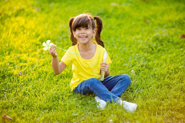 Linda niña india verano en el césped soplando pompas de jabón