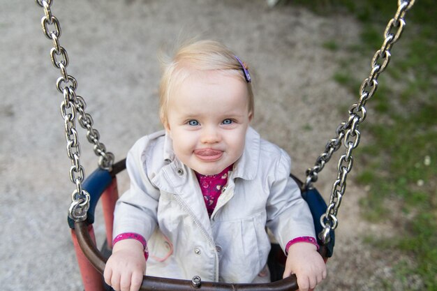 Linda niña jugando en los columpios