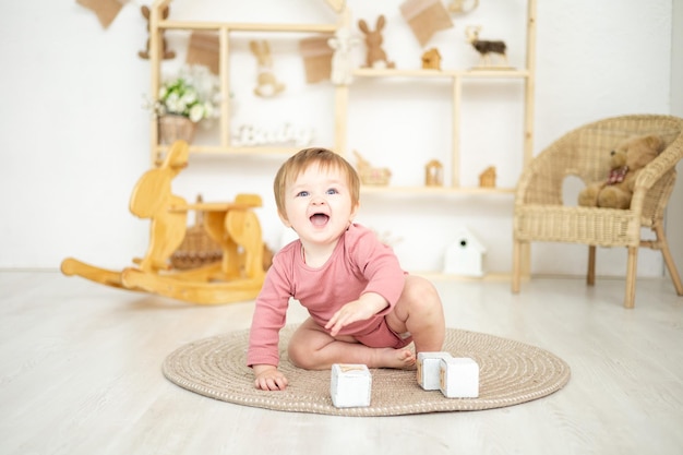 Linda niña jugando con juguetes naturales de madera en la habitación de los niños en casa juguetes educativos para el interior de la habitación de los niños