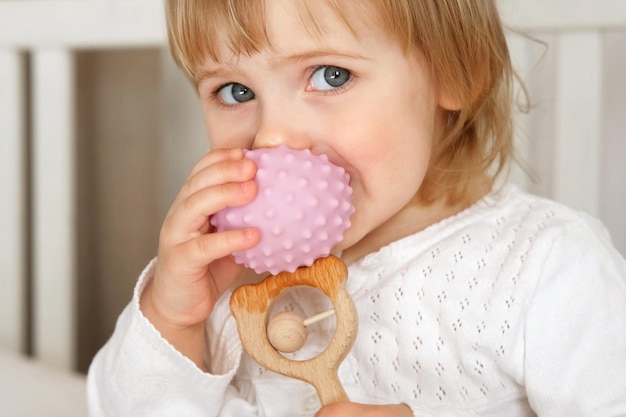 Foto linda niña jugando juguetes táctiles de madera y silicona. la mano del niño pequeño juega con la pelota de masaje sensorial. mejora el proceso físico cognitivo. desarrollo cerebral. juguete para la dentición.